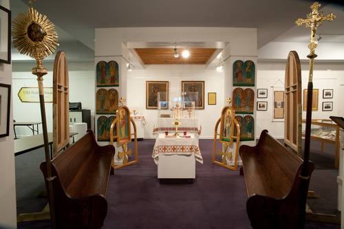 Visible in this photo are the six icons of the Apostles, which are displayed in the icon wall of this exhibit. Also, the icons that appear in the “Deacon’s doors” in this exhibit are from this older icon wall - although the doors have since been re-built as part of a new icon wall. The processional fan and cross that mounted on the end of the pews inside the church date from the earliest years of the parish. These pews are also from the Holy Ghost Ukrainian Catholic church. They have been refinished in honor of the parish’s centenary.
The stained glass windows in the exhibit are from the original Holy Ghost Ukrainian Catholic Church, built in 1913.