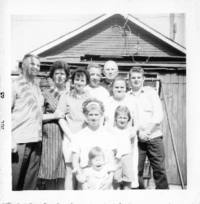 Photograph of a family with Father Zarsky in the background. 