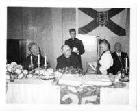 Photograph of celebration at the Ukrainian Hall of Father C. Zarsky's silver jubilee. Young boy presenting something to Father Zarsky.